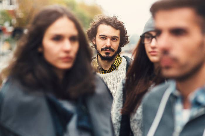 Group of four friends walking, one man in focus with a beard and a sweater