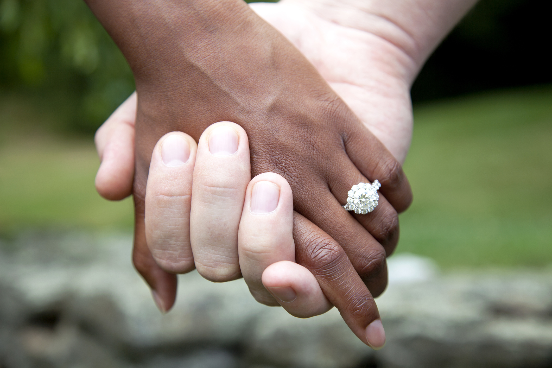 Two people holding hands, one wearing an engagement ring