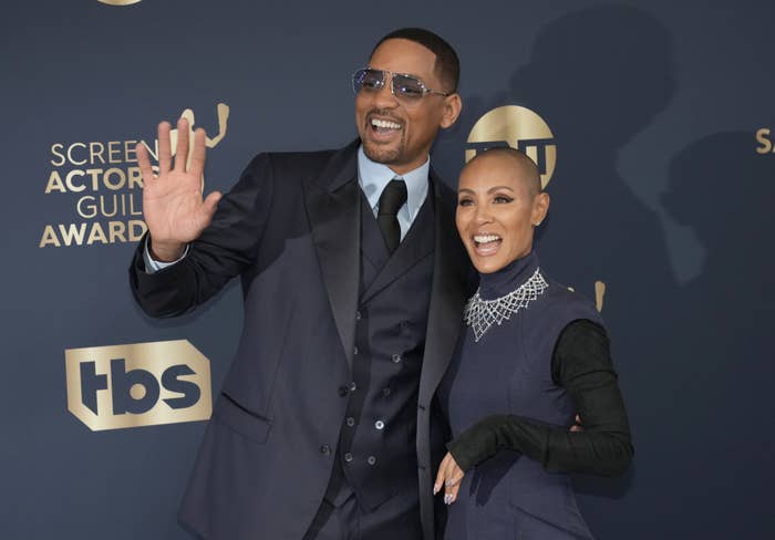 Will Smith and Jada Pinkett Smith pose together, waving and smiling at a SAG Awards event