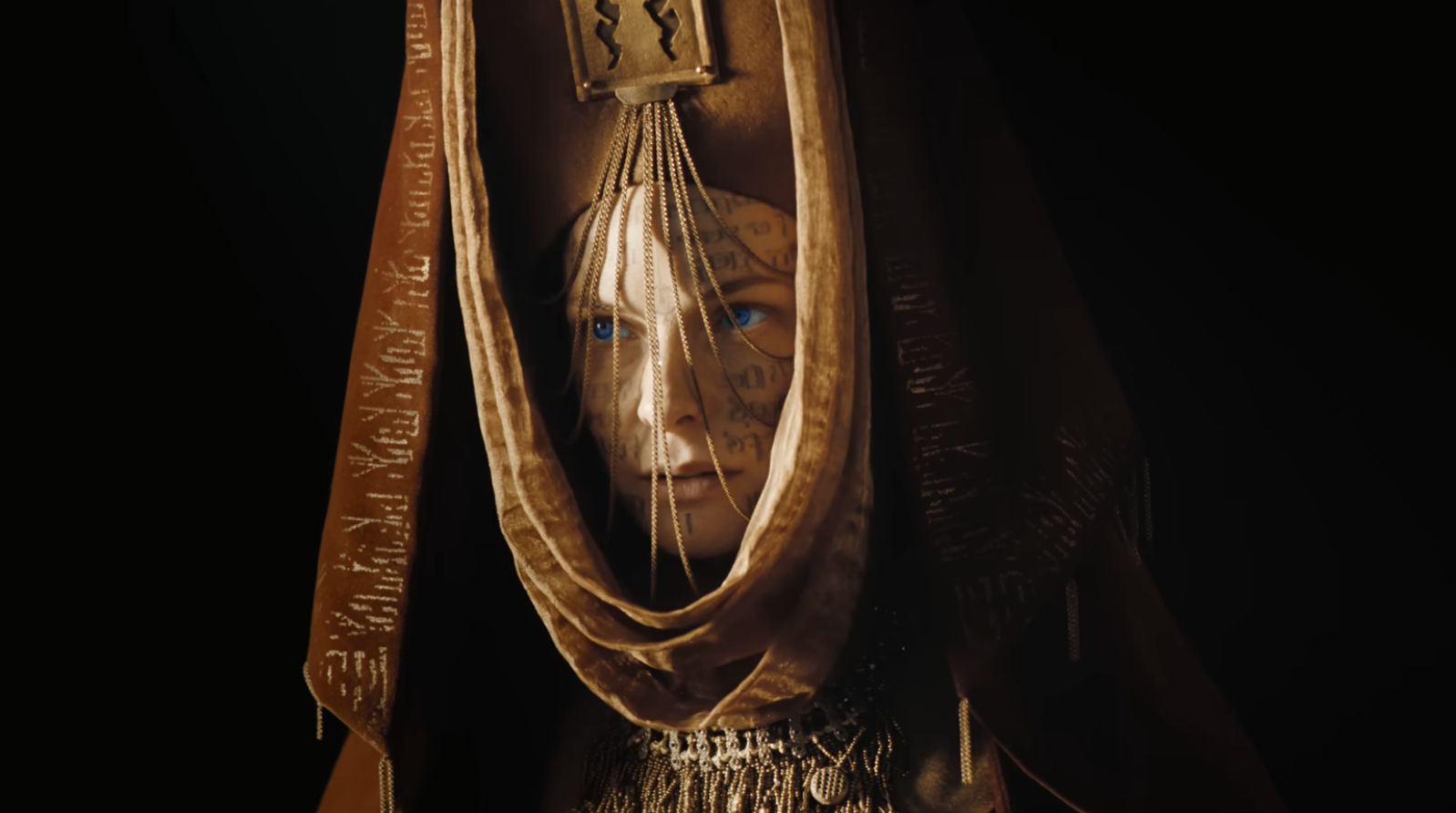 Personaje con tatuajes en el rostro viste capa dorada con texto, escena cinematográfica