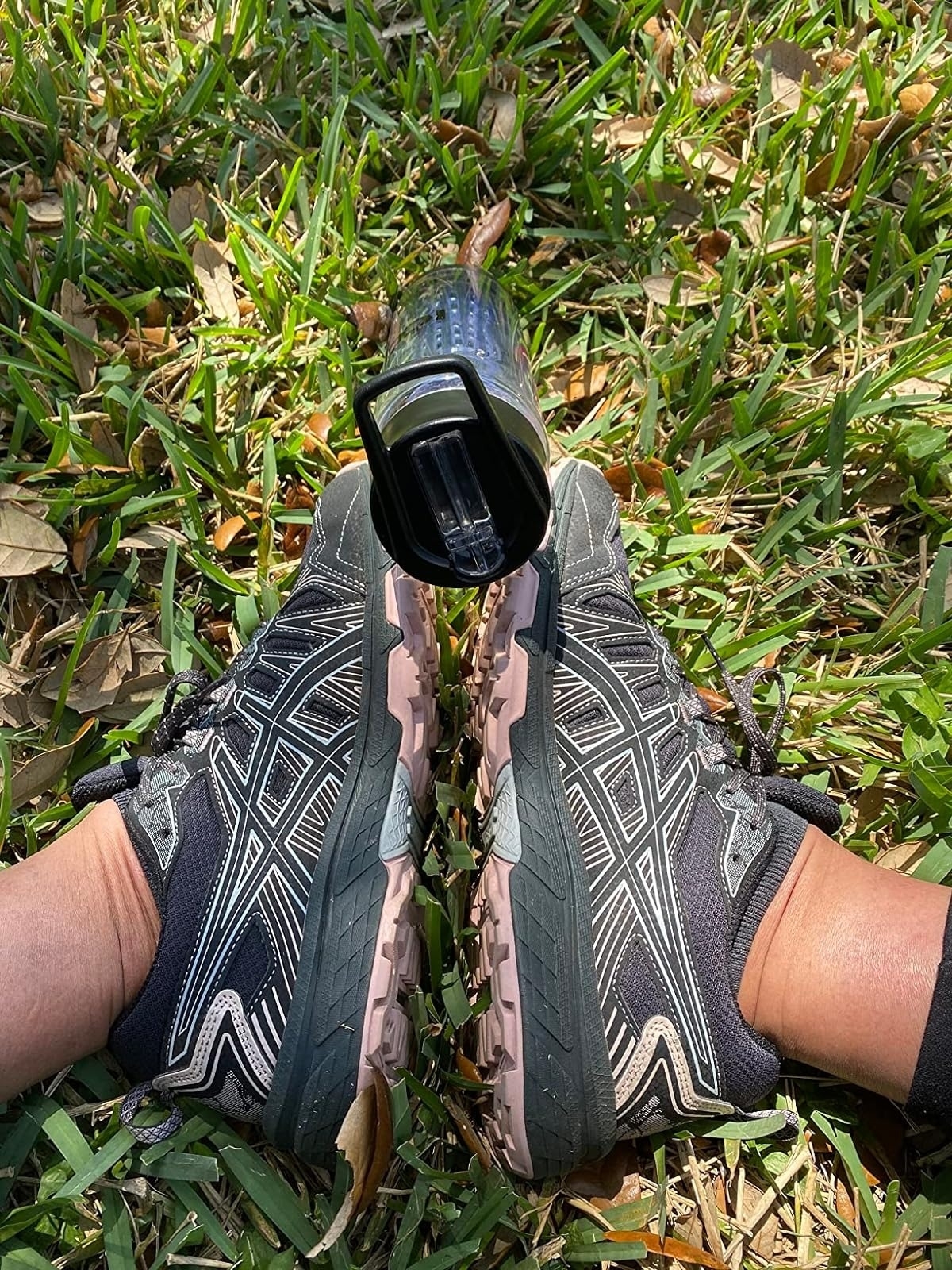 Workout shoes on grass with a portable speaker attached to one shoe