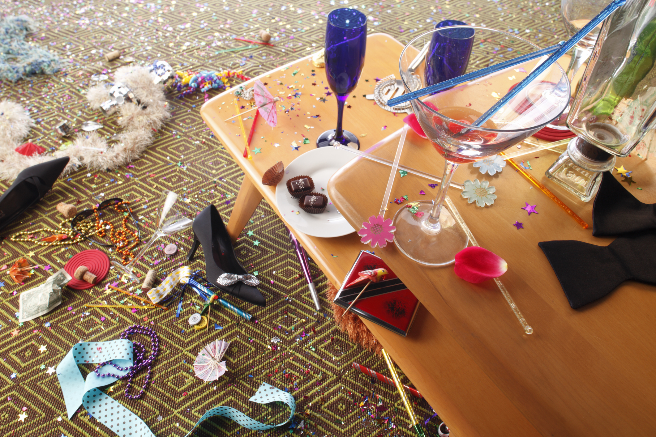 After-party table with scattered party hats, cups, beads, and confetti