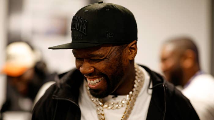 50 Cent in black cap and gold chain necklace laughing
