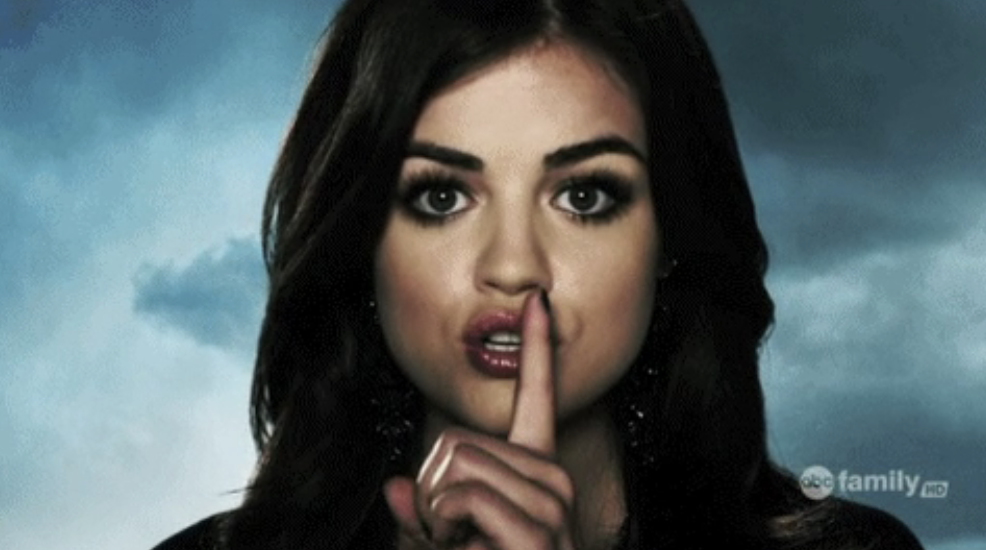 Character Aria Montgomery from &#x27;Pretty Little Liars&#x27; with a finger over lips in a &#x27;shh&#x27; gesture