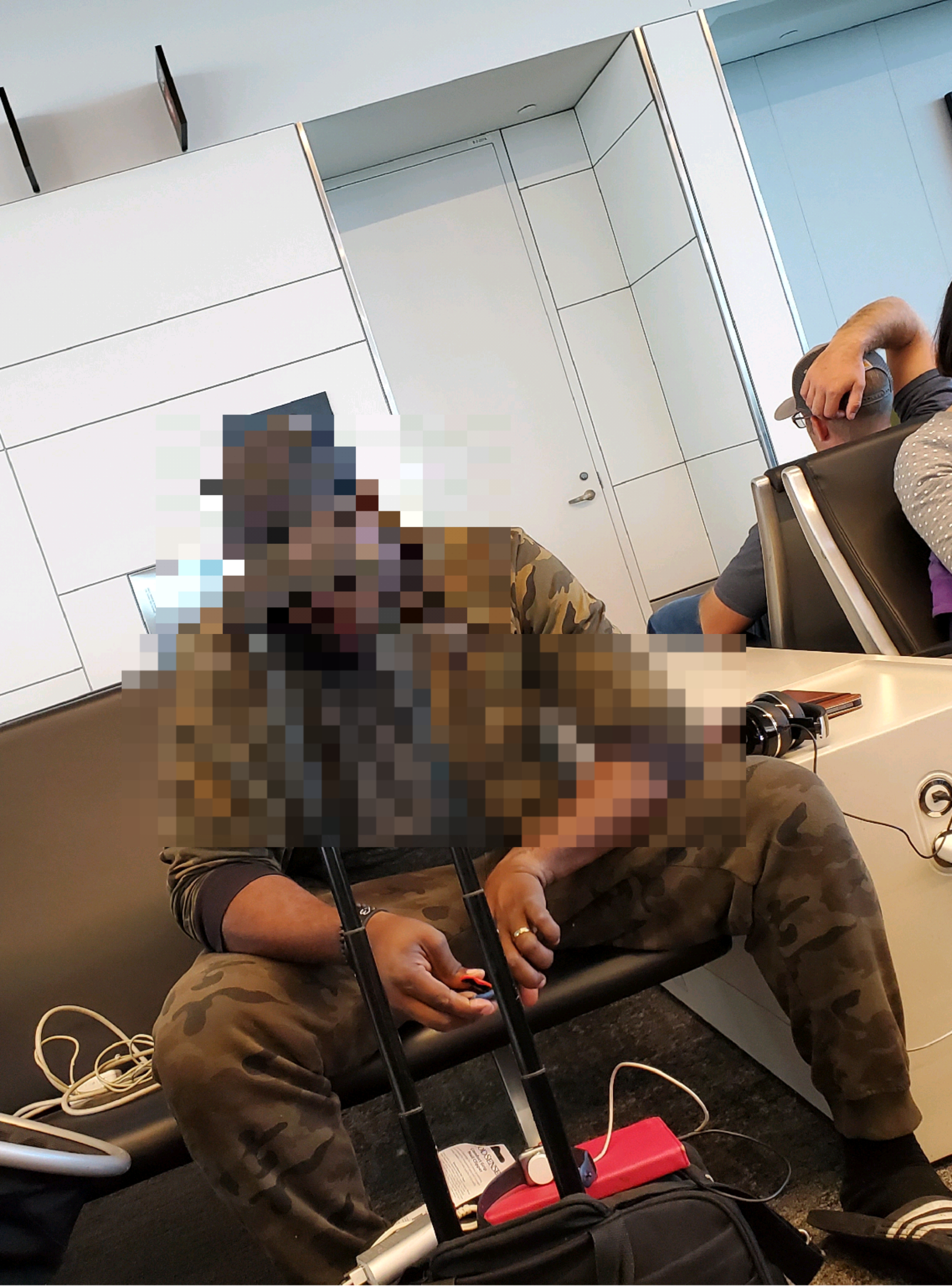 Person with a pixelated face, sitting in an airport terminal clipping his fingernails