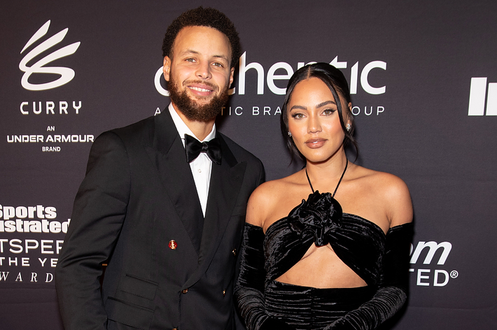 Stephen Curry and Ayesha Curry smiling in formal attire at a Sports Illustrated event