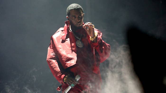 Performer on stage in a red jacket holding a microphone, mid-performance with dramatic lighting