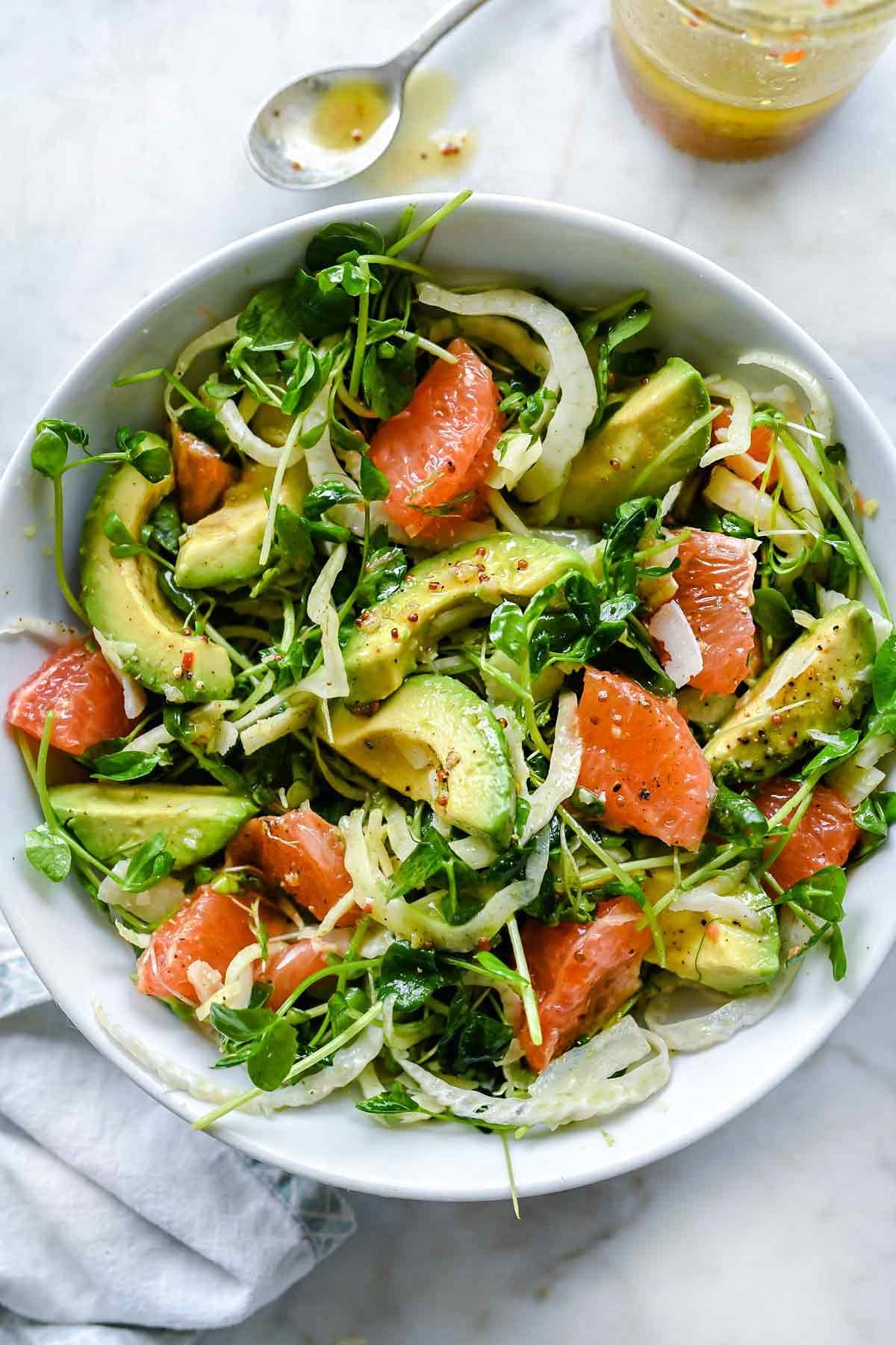 Bowl of avocado salad with grapefruit and mixed greens, dressed with vinaigrette