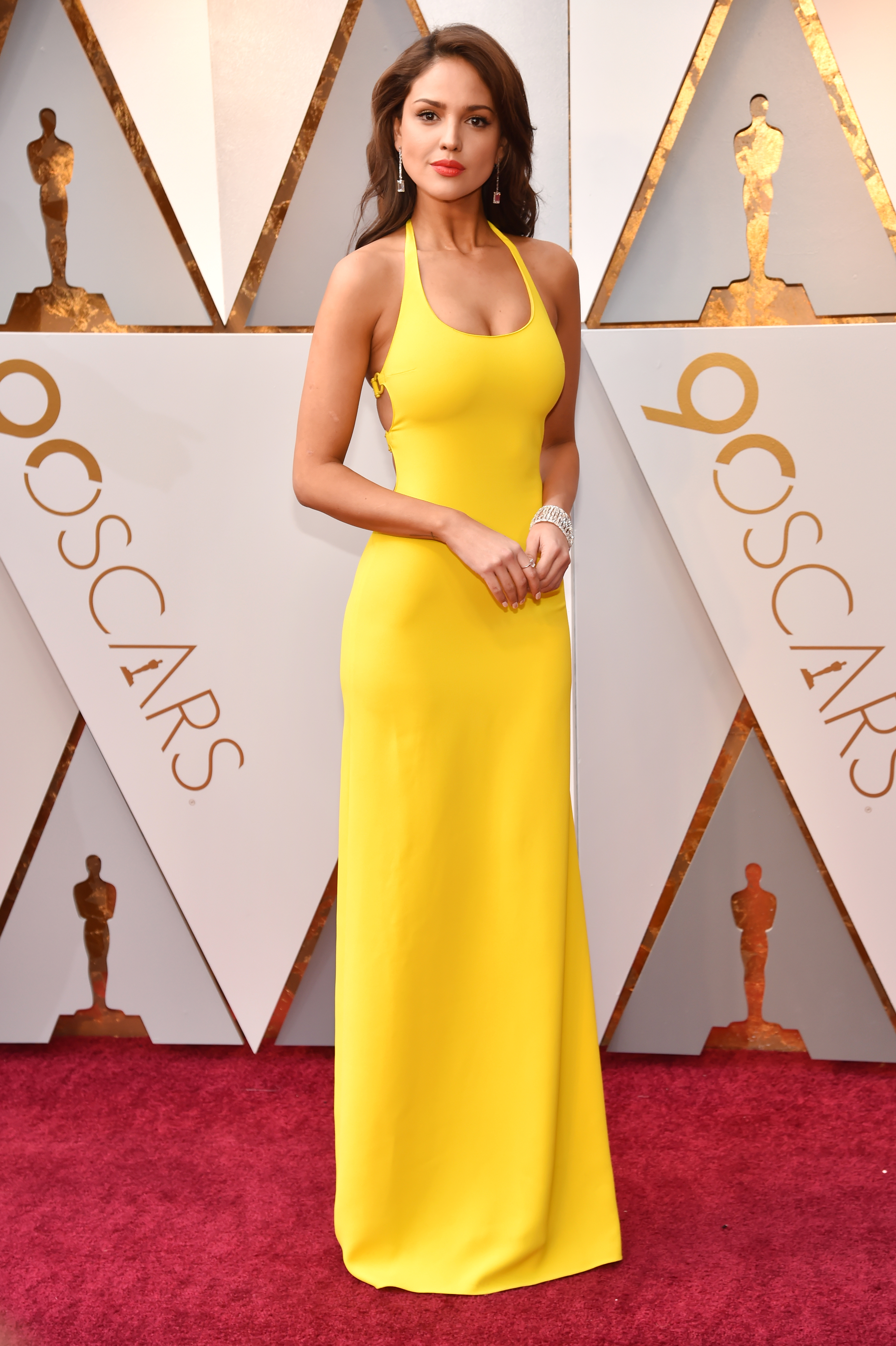 Mujer famosa posa en la alfombra roja en un elegante vestido largo amarillo