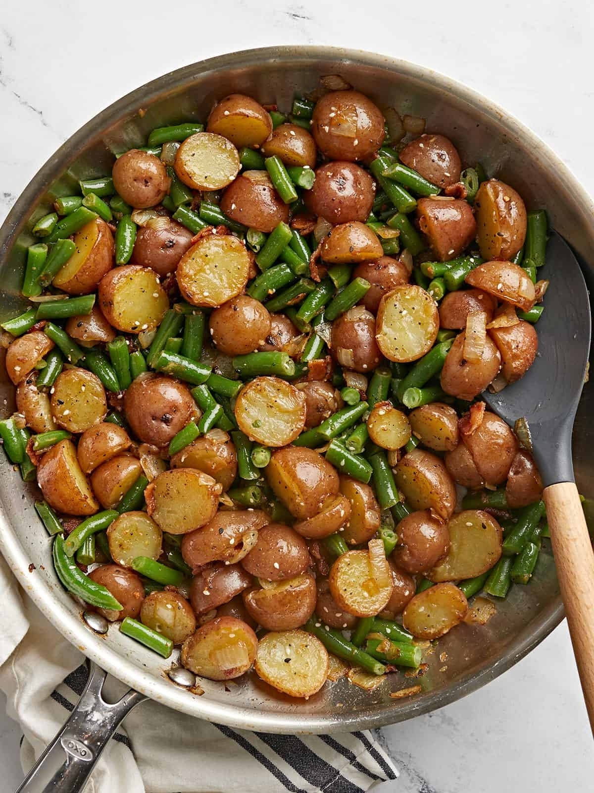 Cooked green beans and halved potatoes in a pan