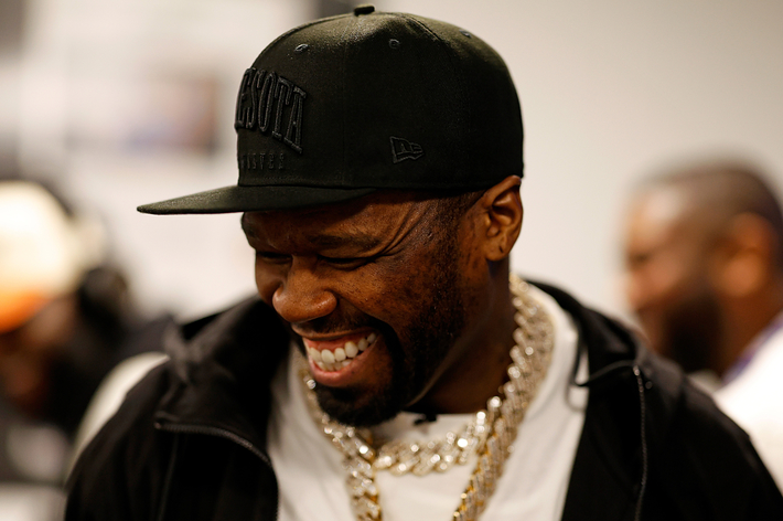 50 Cent in black cap and gold chain necklace laughing