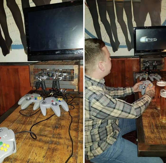 Person plays N64 under wall-mounted controllers; a social gaming setup at a bar