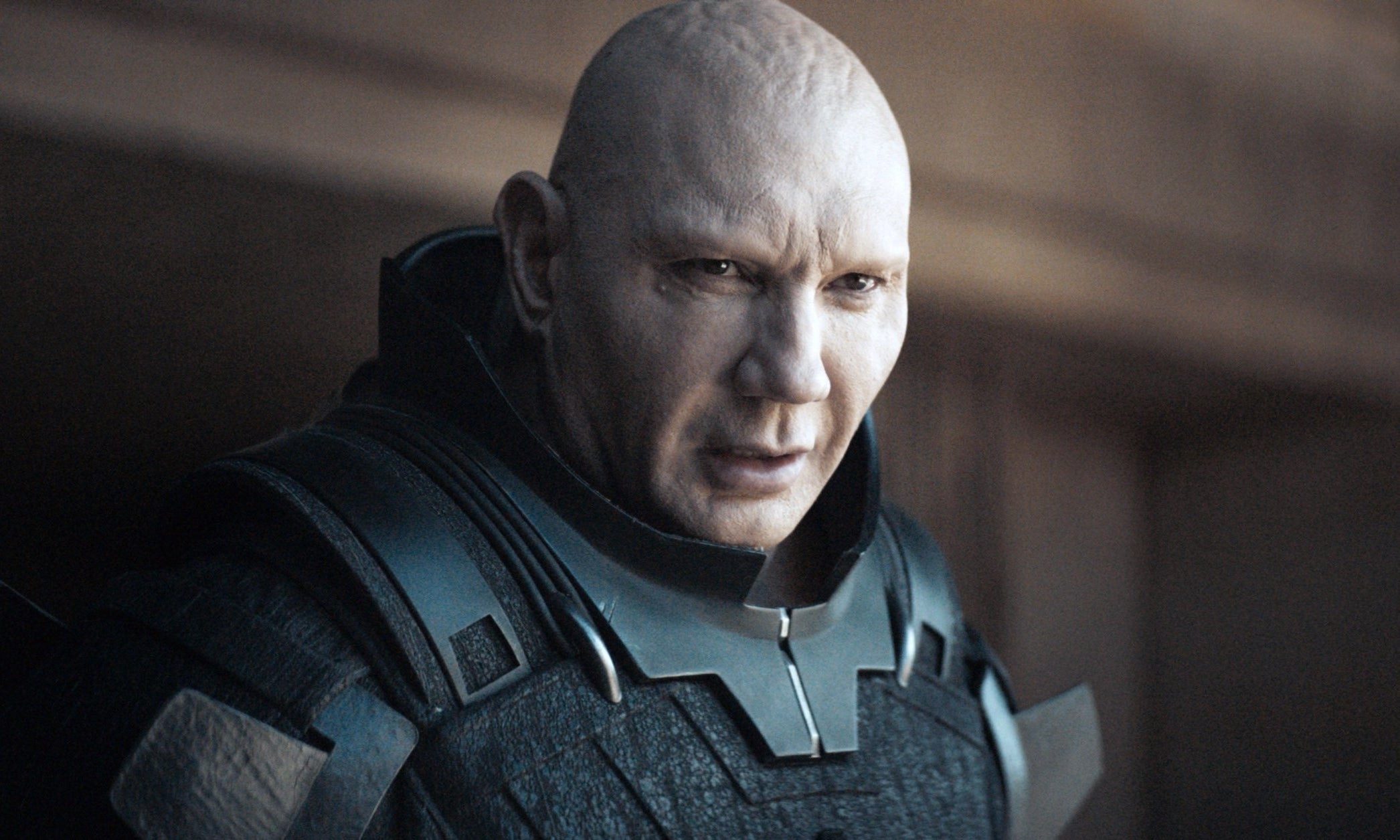 Actor in character as a bald, futuristic warrior in armor, intense expression, scene from a TV or movie