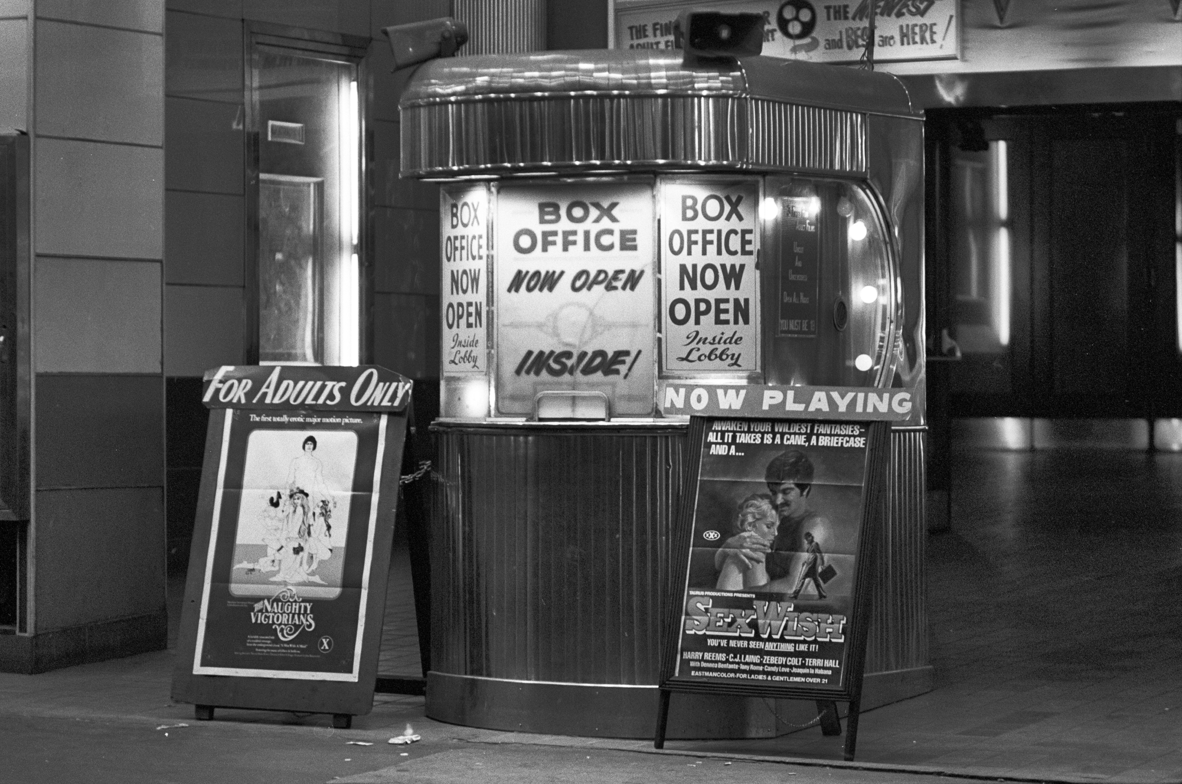 Vintage movie theater box office with promotional posters and &quot;Box Office Open&quot; signs
