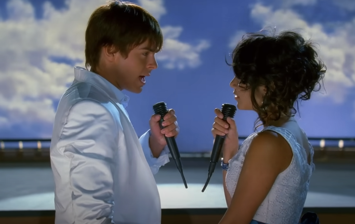Two characters from High School Musical, a male and a female, singing together with microphones