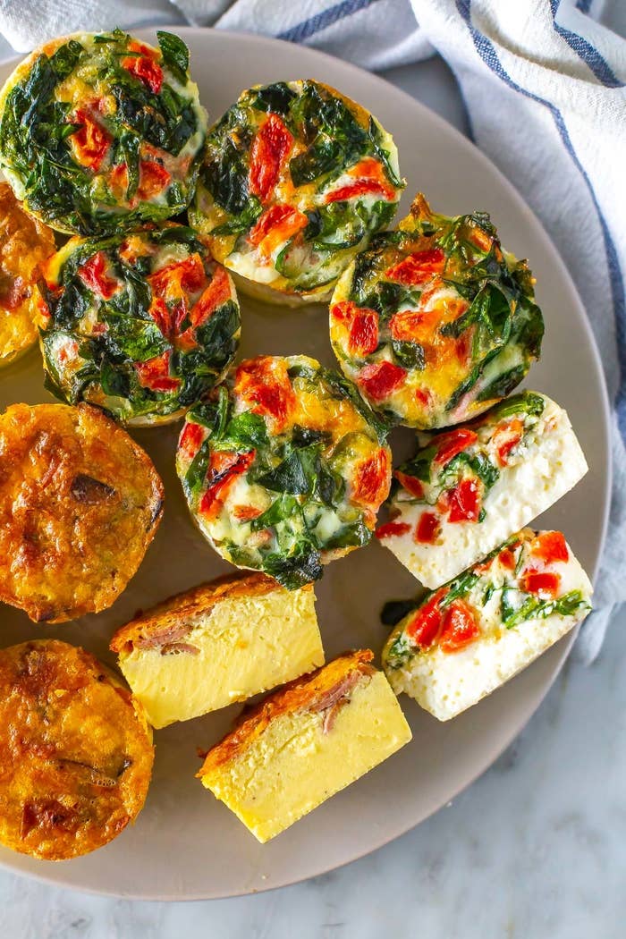 A plate with an assortment of breakfast foods including egg muffins and sliced frittata
