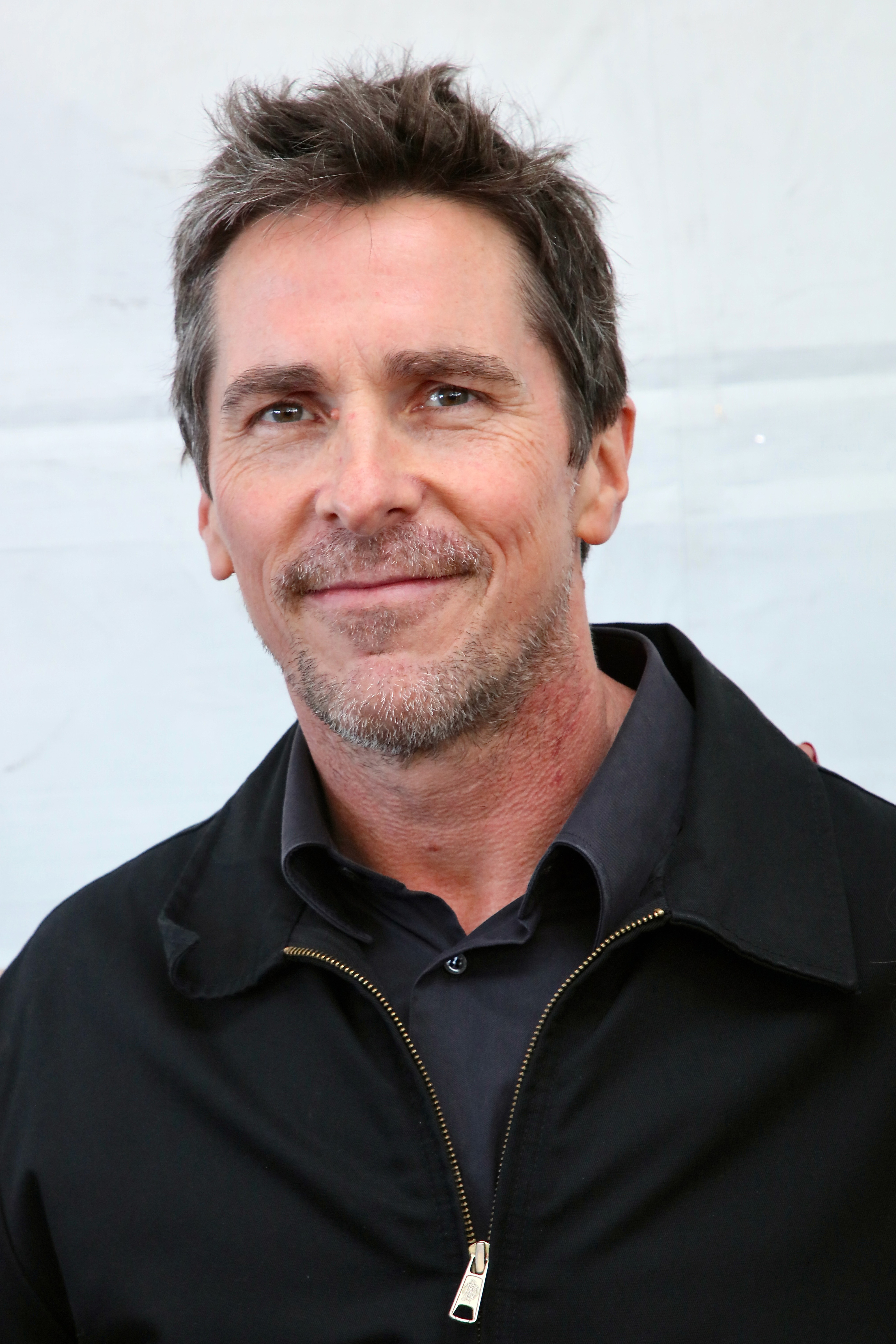 A close-up of Christian Bale smiling at the camera
