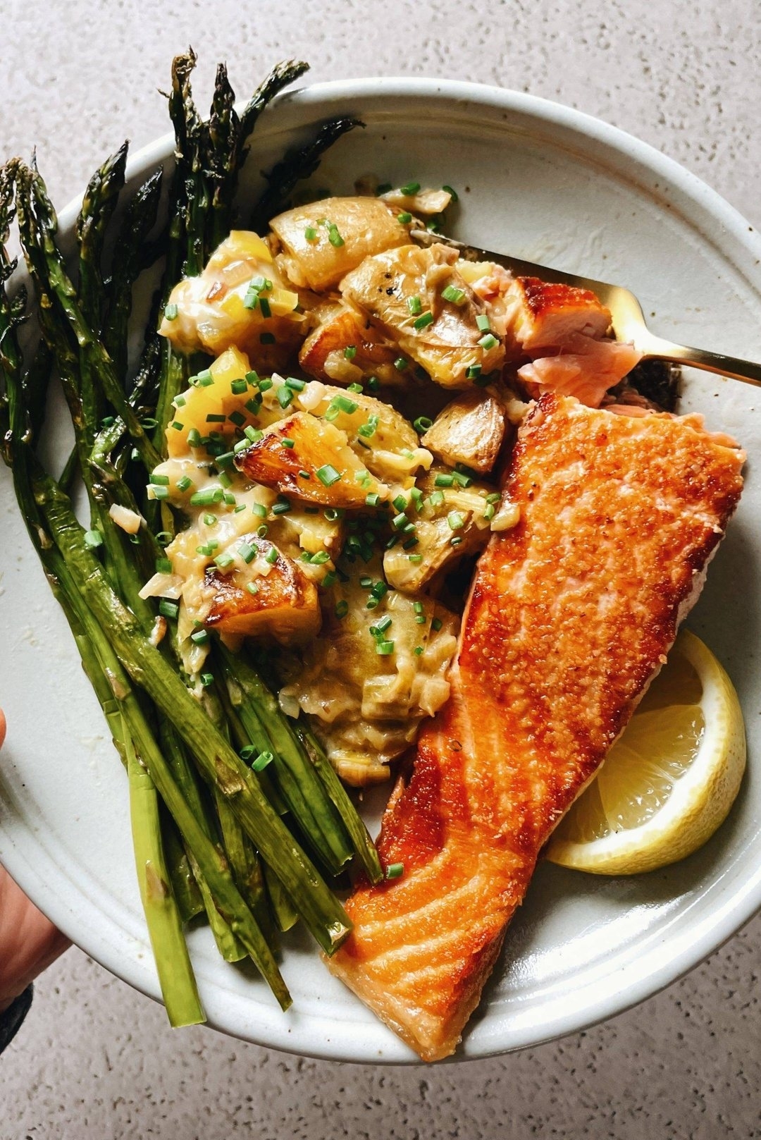 Grilled salmon and asparagus on a plate with lemon wedge and sauce