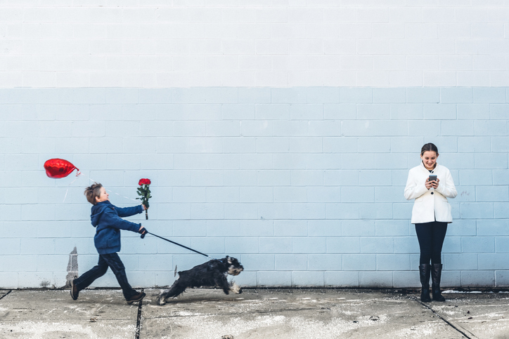 Child walks dog carrying a rose while woman reads a message, emotions of anticipation and affection conveyed
