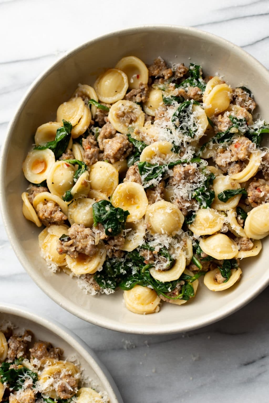 Bowl of orecchiette pasta with sausage, greens, and grated cheese