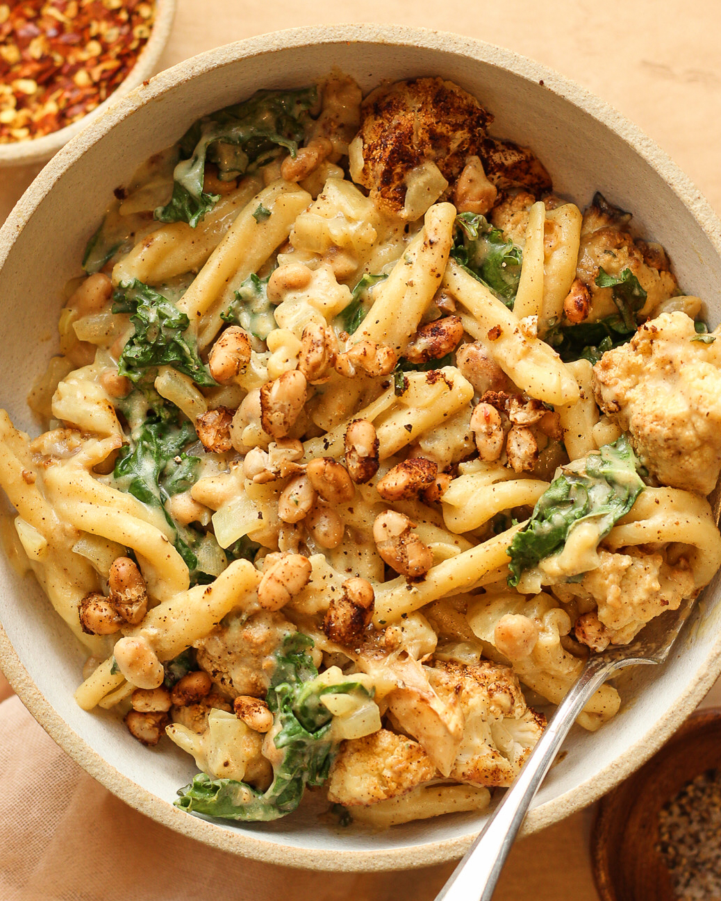 Bowl of mac &#x27;n&#x27; cheese with roasted cauliflower and greens, topped with toasted breadcrumbs