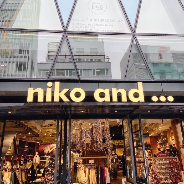 店舗入口上の「niko and ...」のロゴ。ガラス張りの建物で、店内に商品が見える。