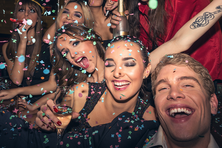 パーティーで紙吹雪を浴びながら笑顔でポーズを取る人々。