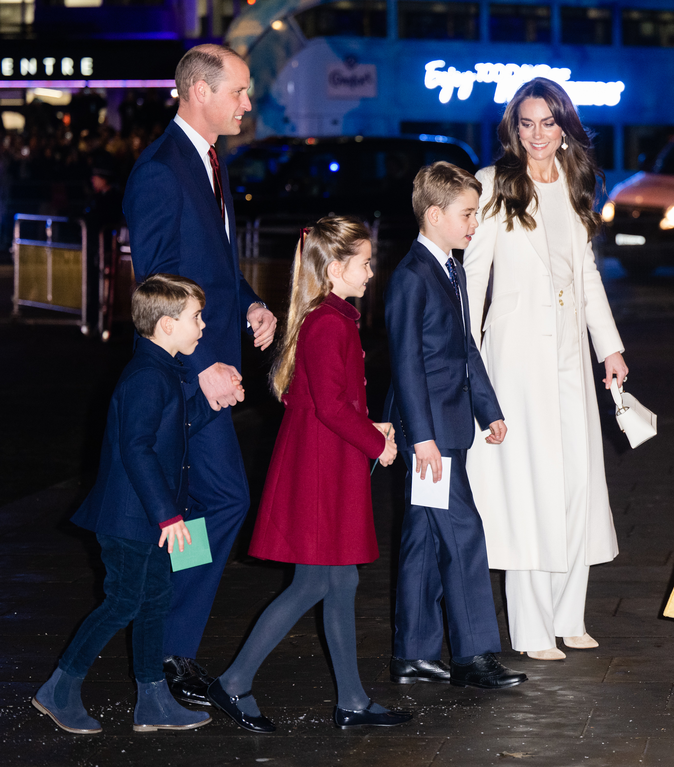 Prince William and Kate Middleton with their children walking outside at night for an event