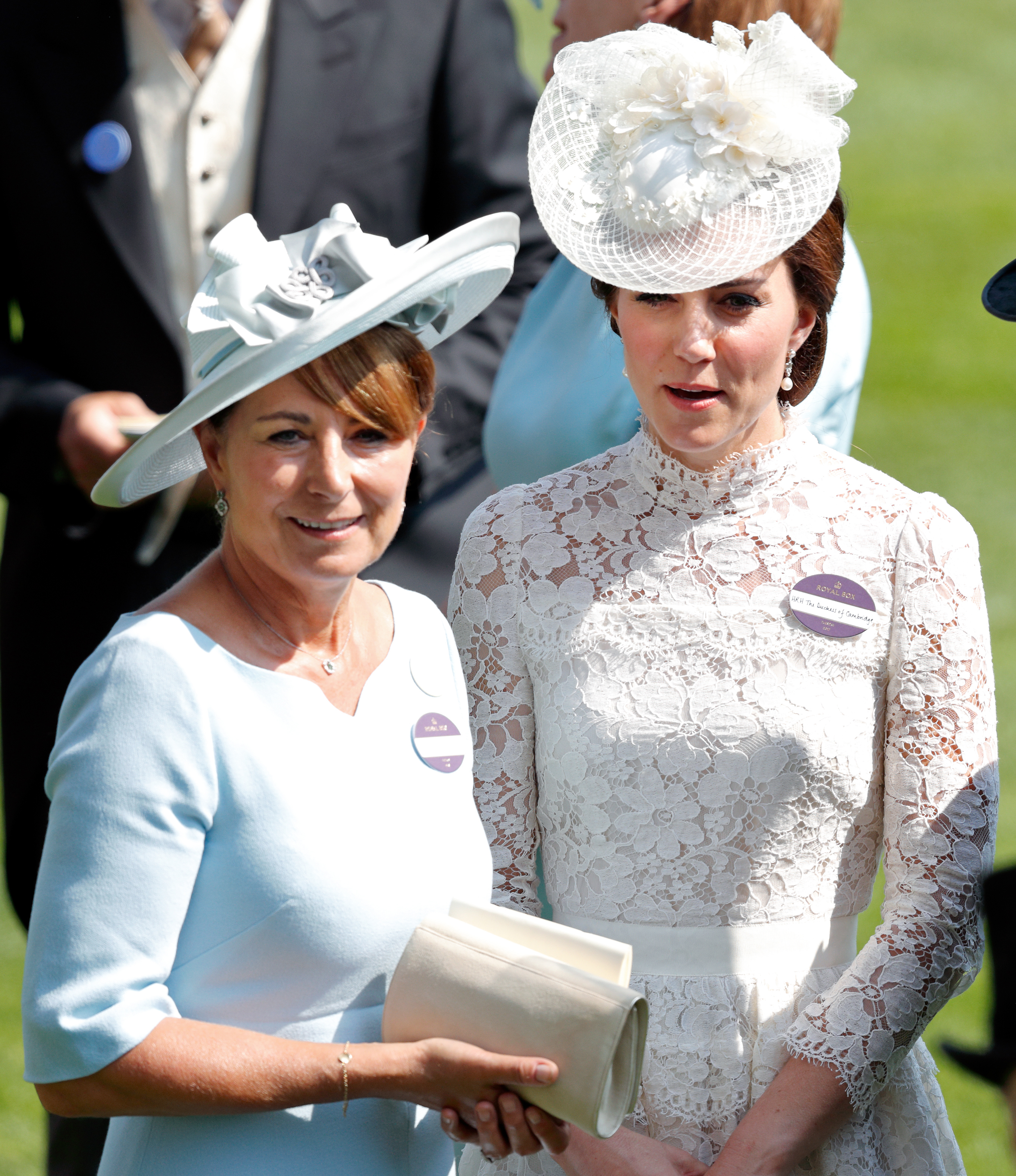 Two women in elegant hats and formal attire at an outdoor event