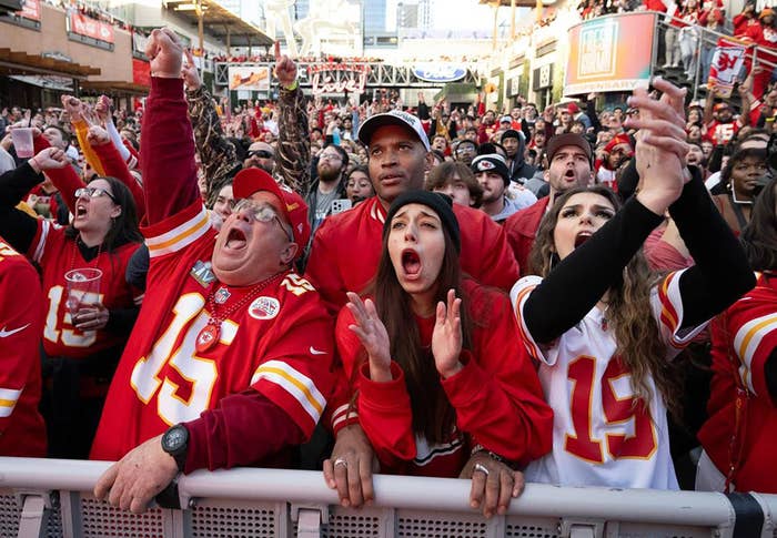 Excited fans in Kansas City Chiefs attire cheering at a game