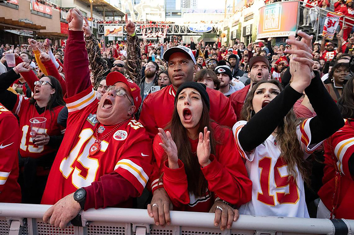 Excited fans in Kansas City Chiefs attire cheering at a game