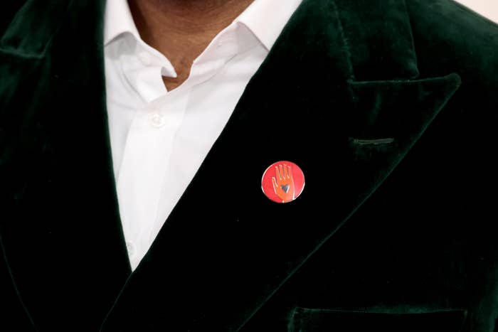 Close-up of a person in a velvet blazer with a graphic pin on the lapel