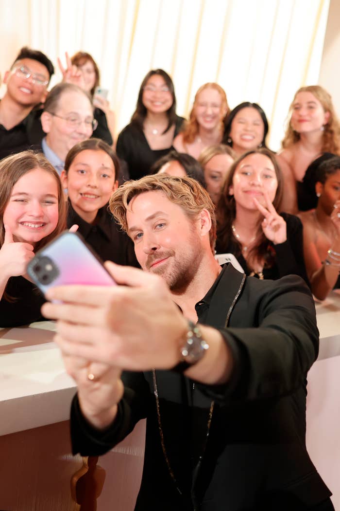 Man in formal attire taking a selfie with a group of smiling people in the background