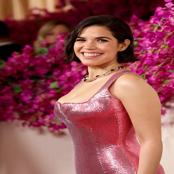 America Ferrera smiles in a sequined dress at an event with floral background