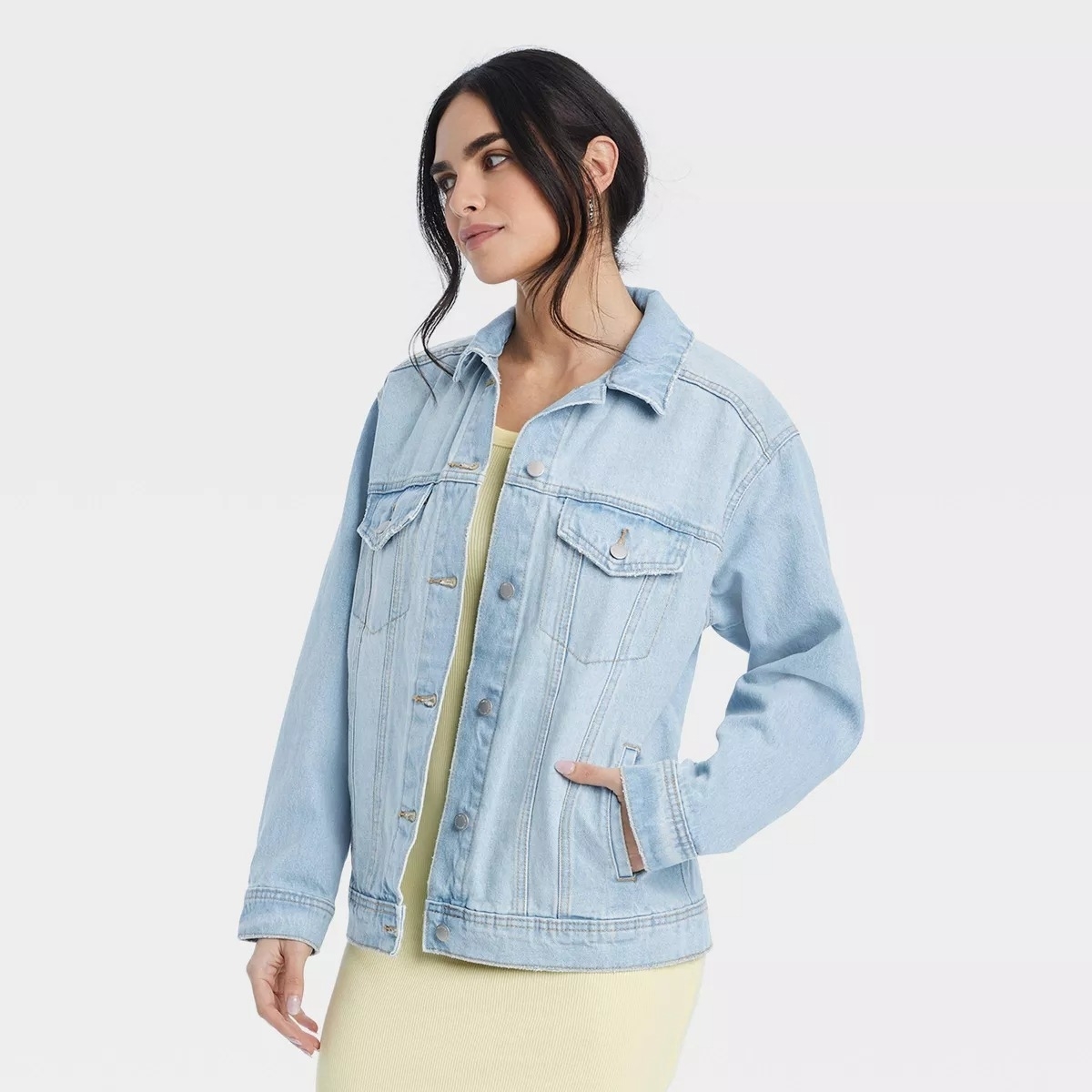 A model in a denim jacket over a yellow top,