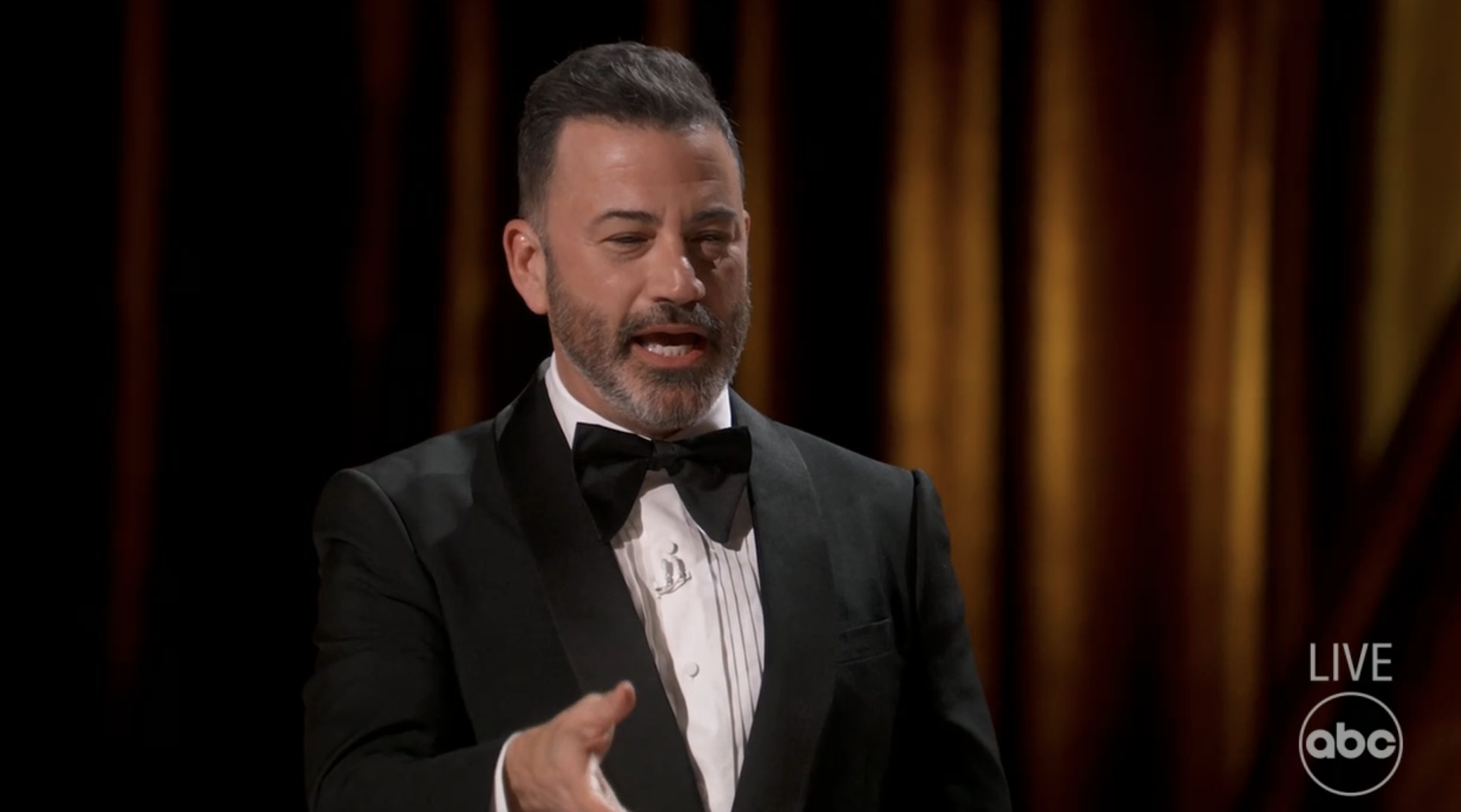 Jimmy Kimmel in black tuxedo hosting on stage