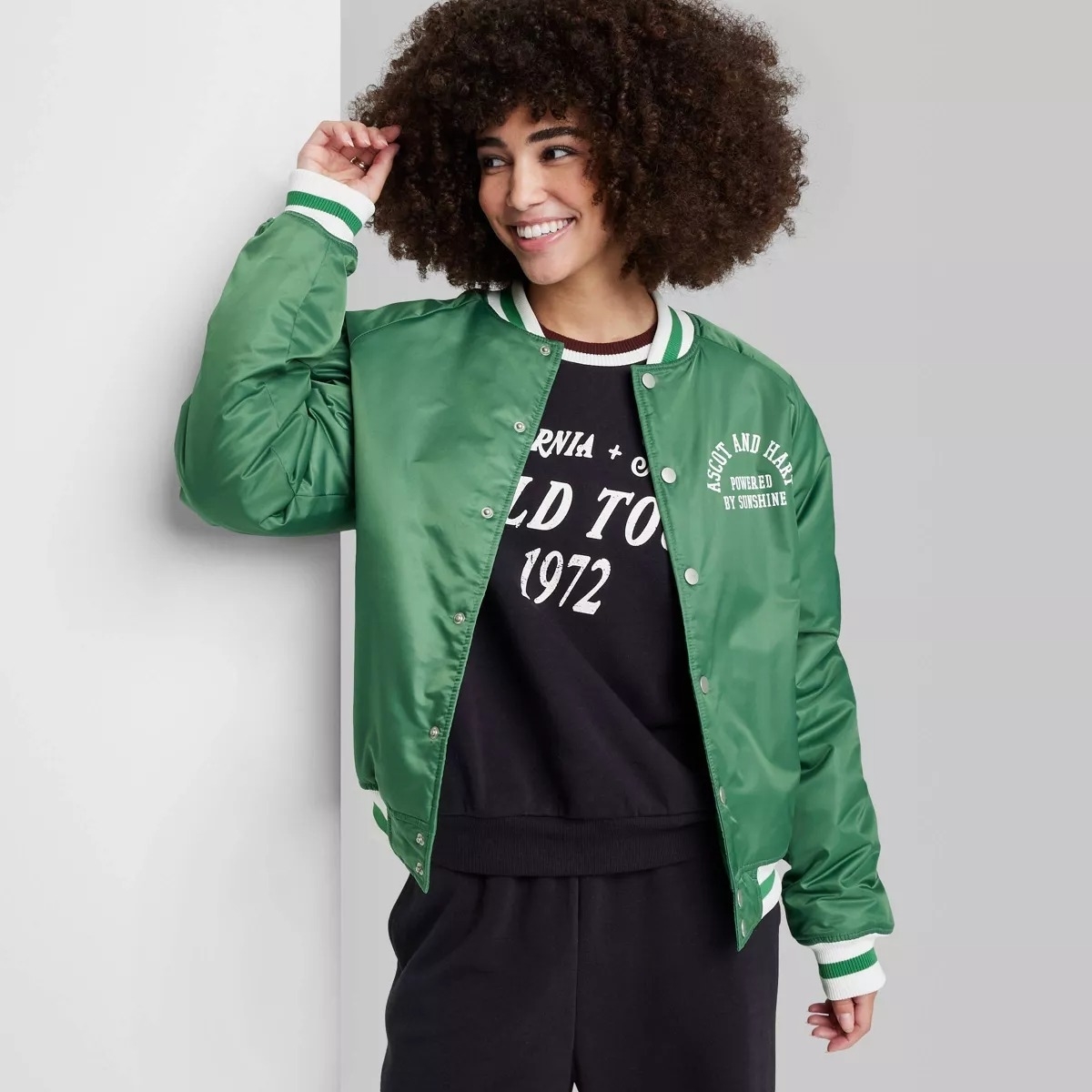 Person in a green bomber jacket with green and white striping at wrists and neck