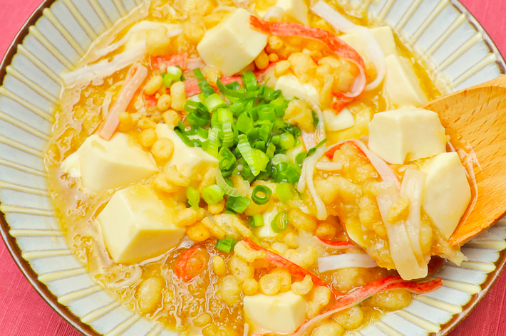 豆腐とネギがトッピングされた均一なスープの上に浮かぶエビと野菜の具が特徴的な和食料理です。