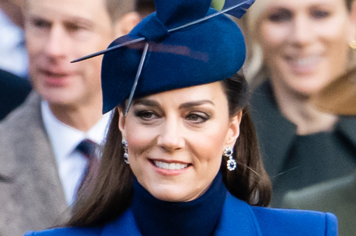 Close-up of Kate Middleton in a formal hat and earrings, smiling at an event