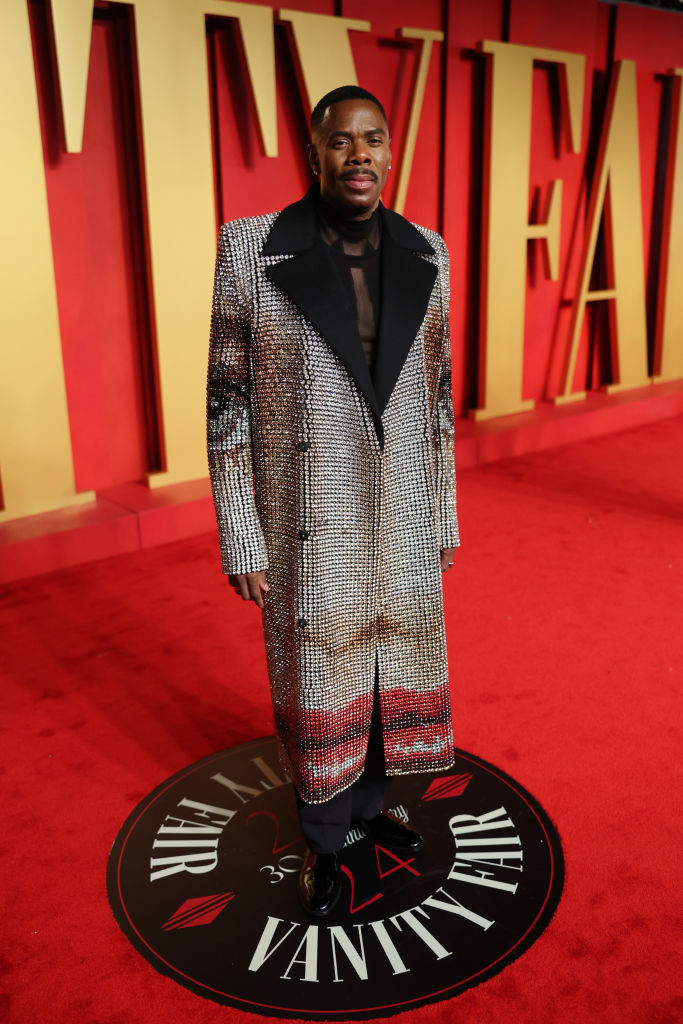 Colman in a sequined coat and trousers standing on a Vanity Fair event carpet