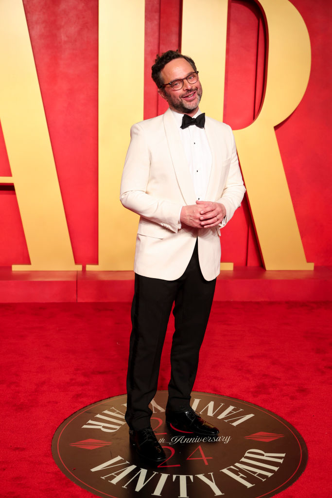 Nick in a white jacket and black bow tie standing on the Vanity Fair red carpet