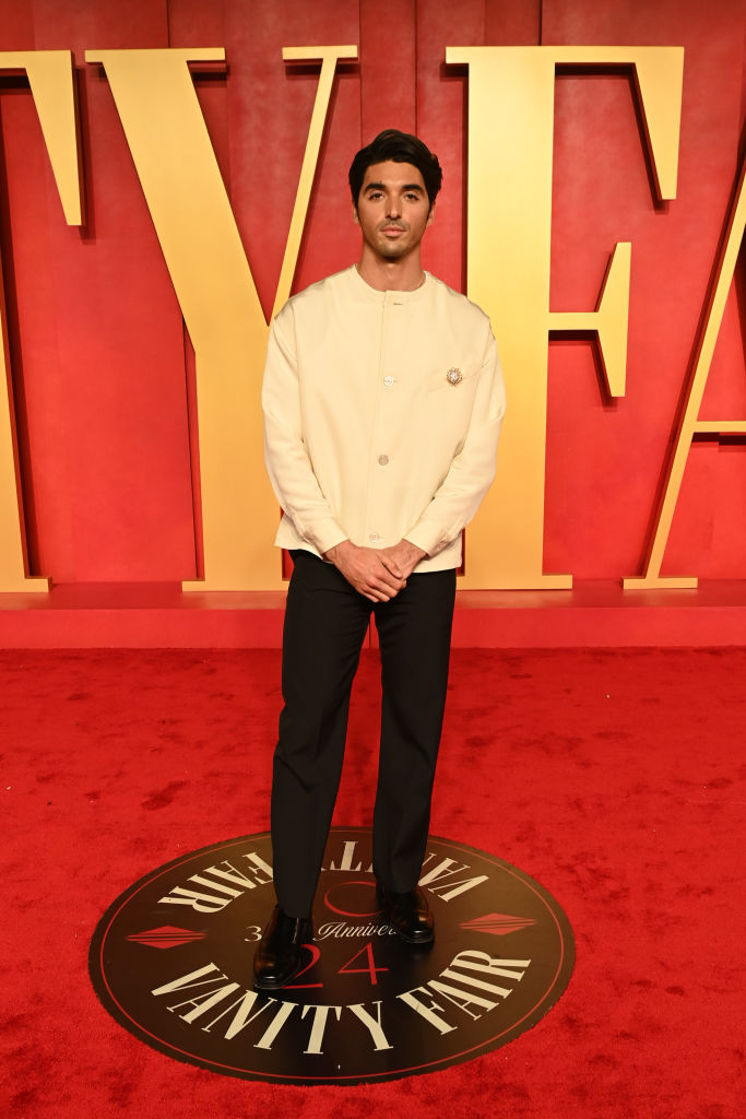 Taylor in a chic cream jacket and black trousers poses on a Vanity Fair event carpet
