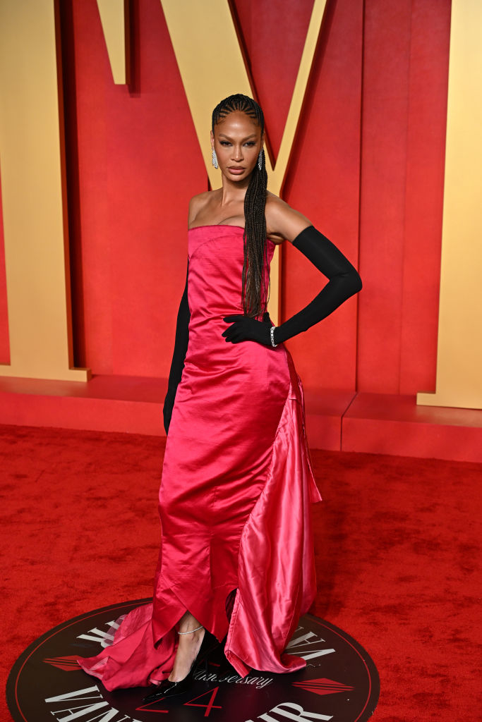 Joan in strapless satin gown with black gloves posing on red carpet