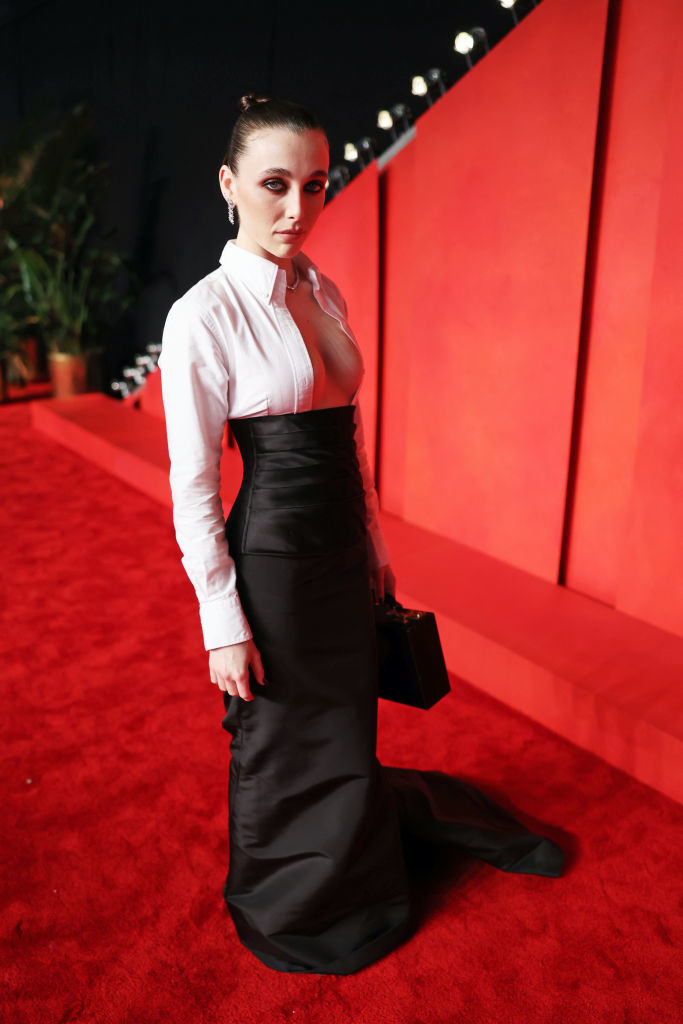 Emma in a white long-sleeved, breast-baring blouse and long black skirt on the red carpet