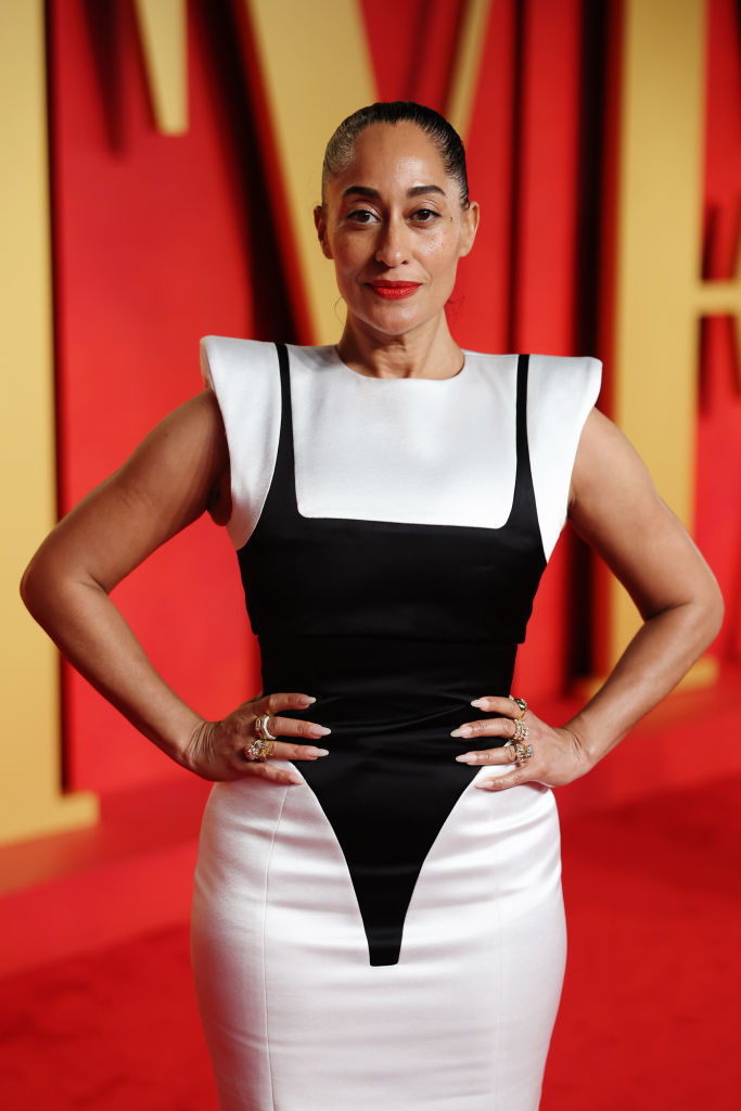 Tracee on the red carpet in a sleeveless black-and-white fitted dress with hands on hips