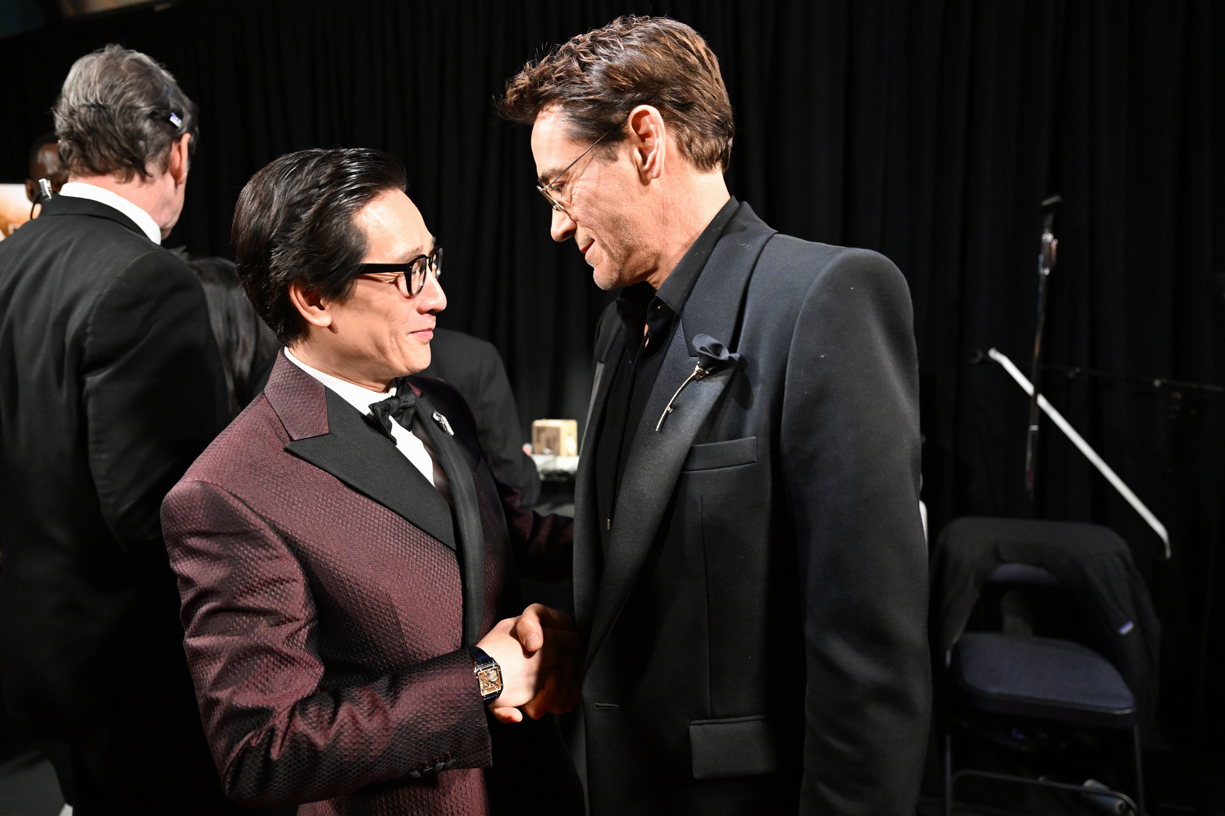 Ke Huy and RDJ in formal suits smiling and shaking hands