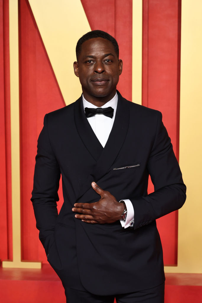 Sterling in a tailored black tuxedo with bow tie, standing, hand over chest
