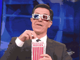 Stephen Colbert wearing 3D glasses and eating popcorn