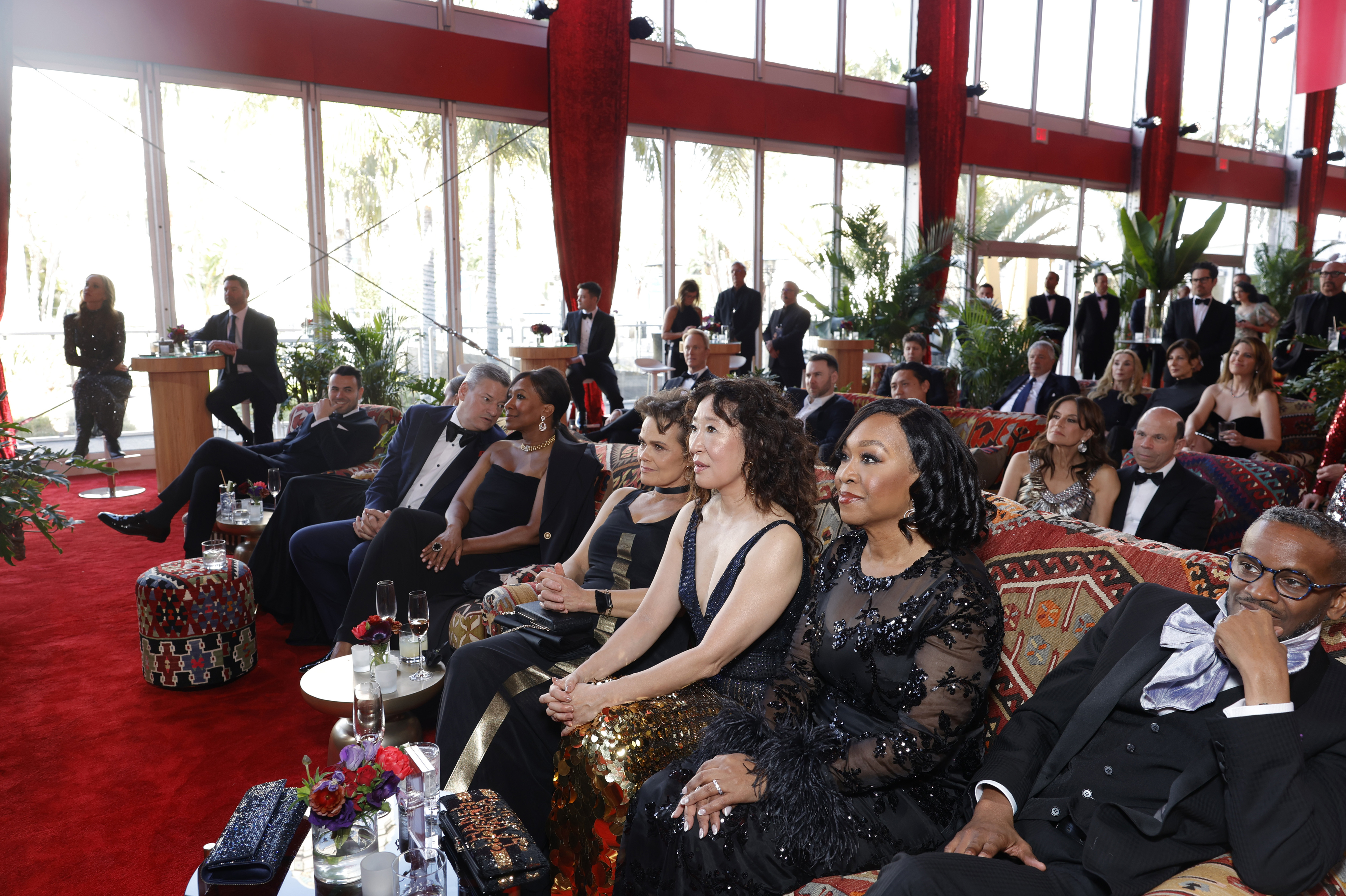 Guests seated at a formal event, including Sandra Oh and Shonda Rhimes, wearing elegant attire