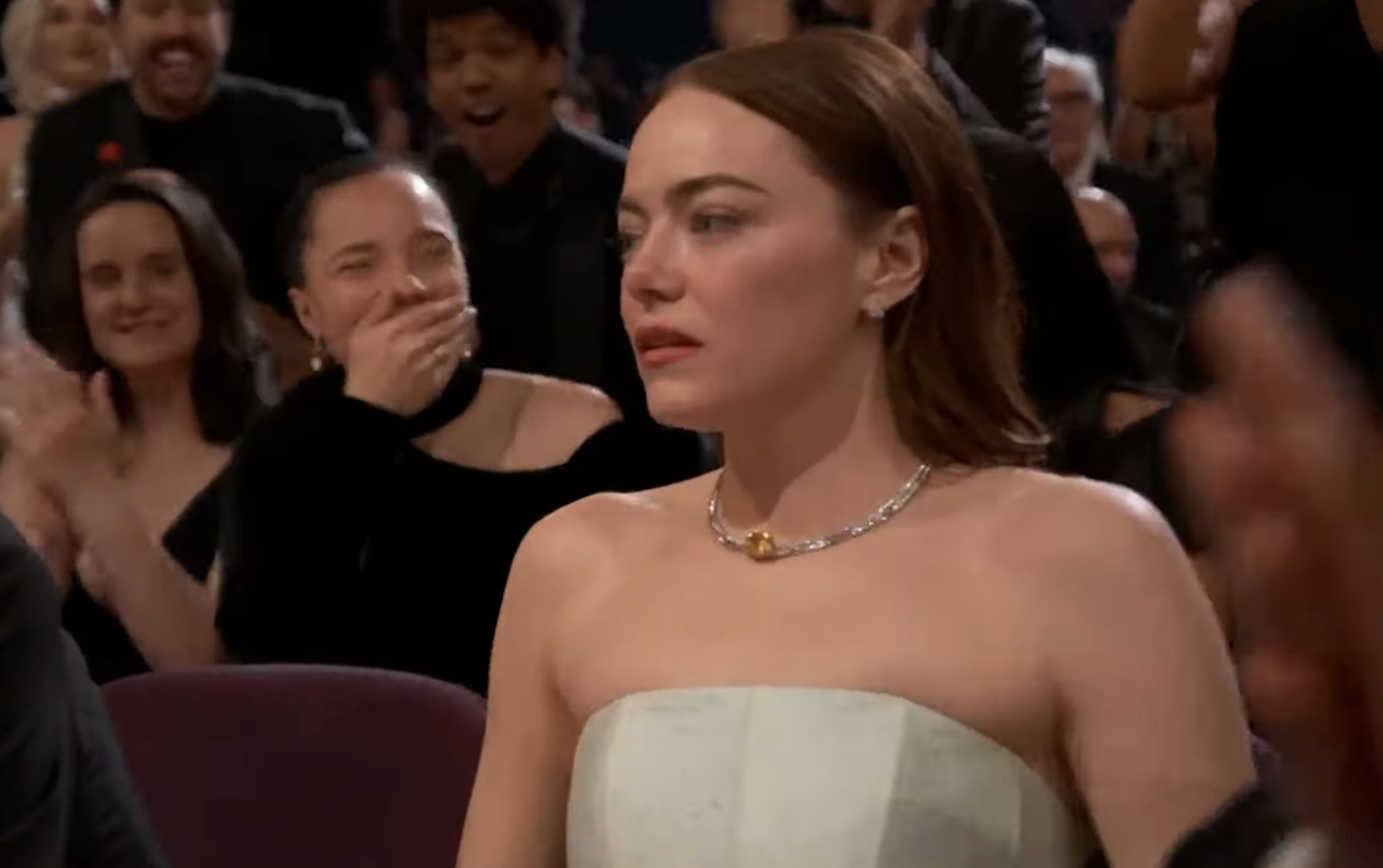 Emma Stone seated at the Oscars, reacting with a surprised expression